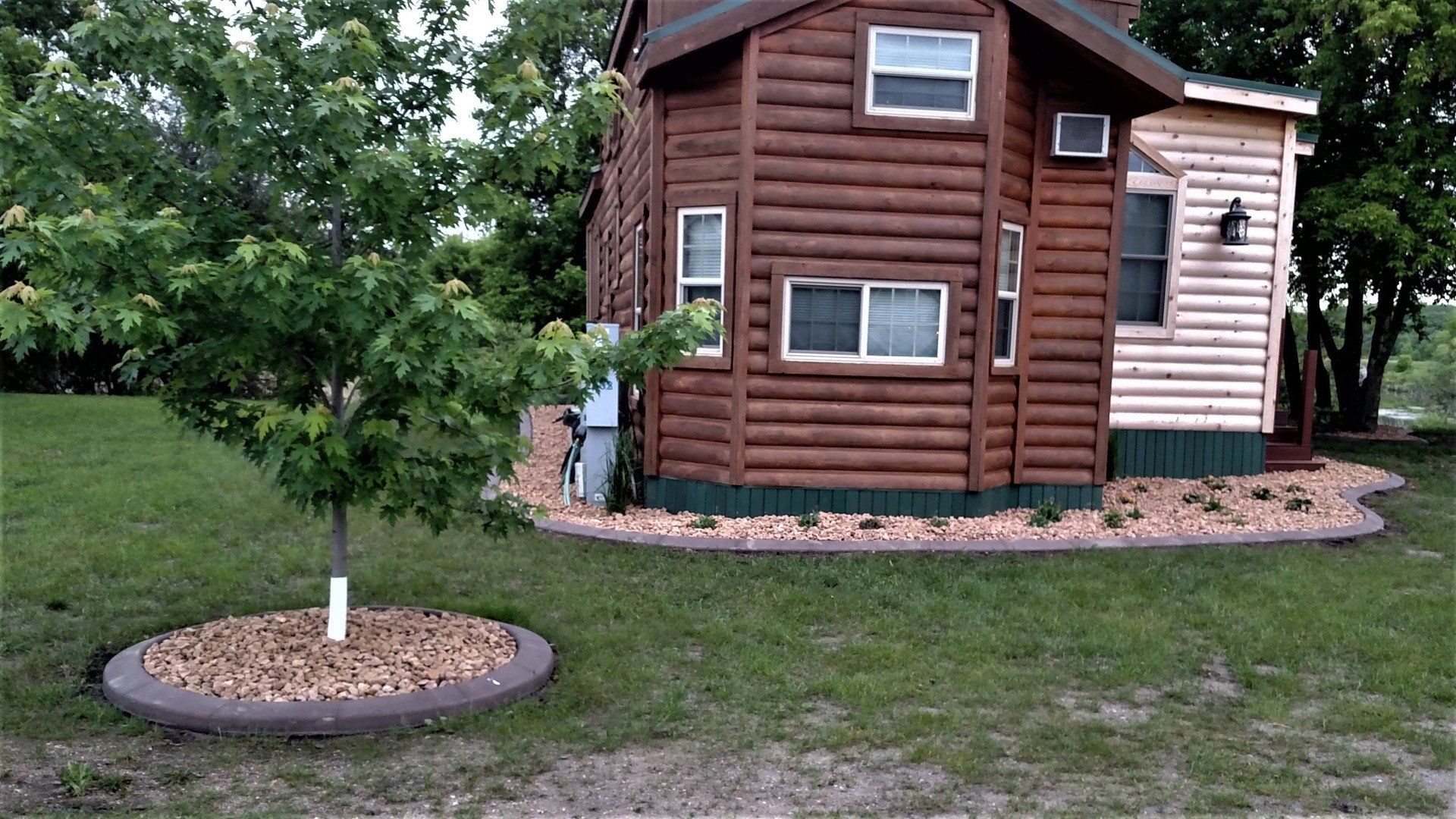 A log cabin with a tree in front of it.