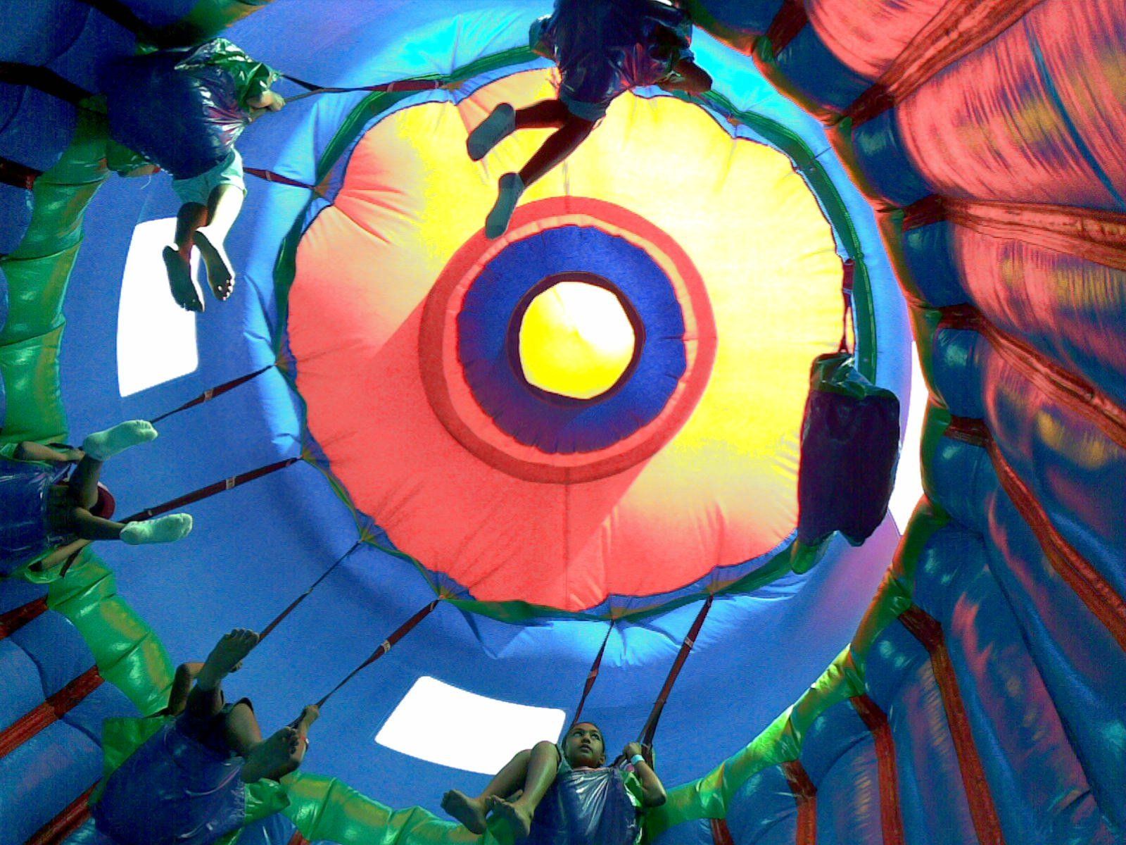 A group of people are flying through a colorful inflatable dome