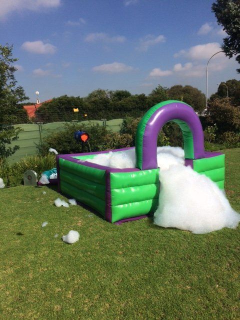 A green and purple bouncy house with foam coming out of it