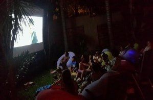A group of people are sitting in front of a large screen.