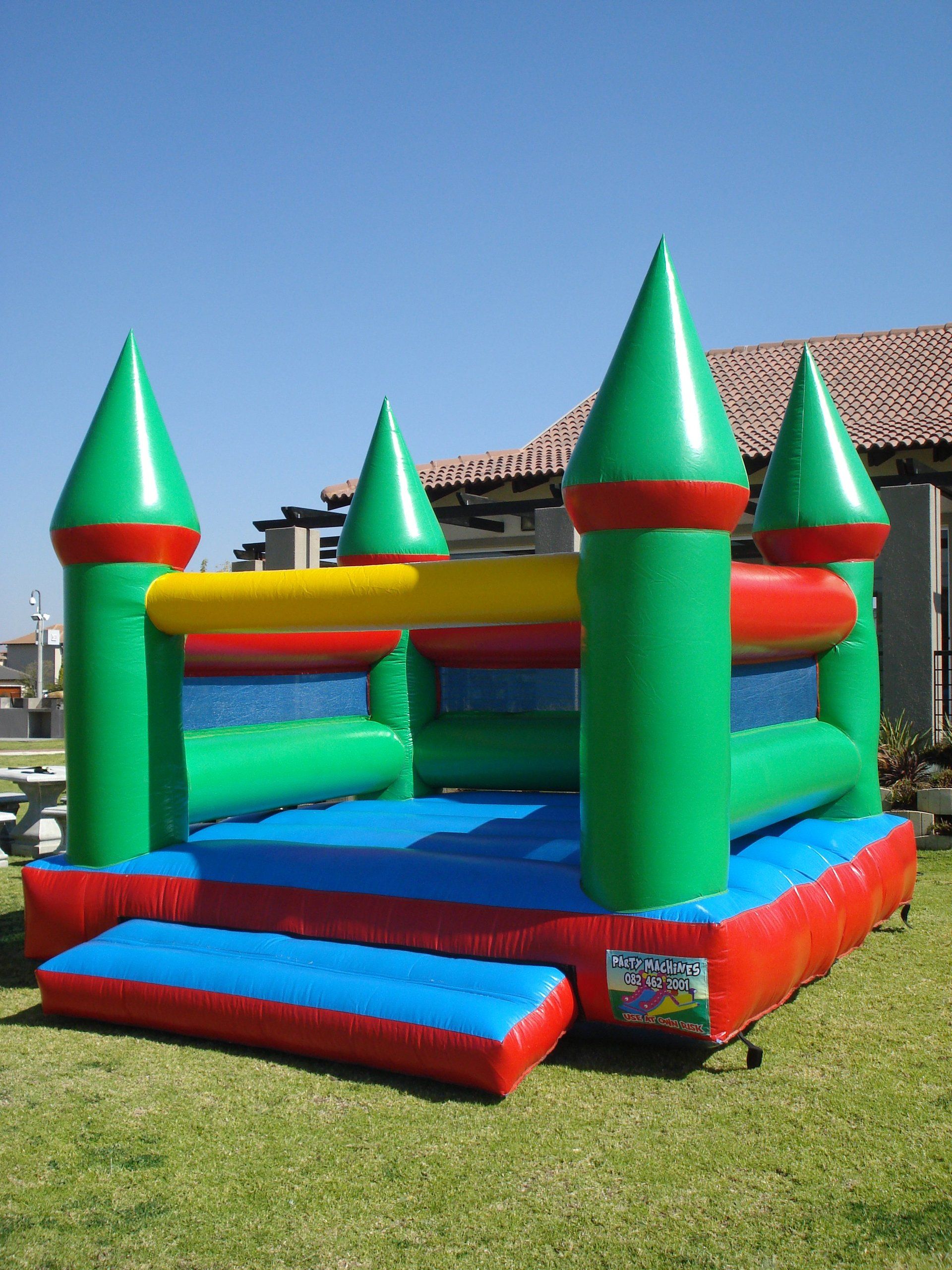 A green and red bouncy castle is sitting in the grass