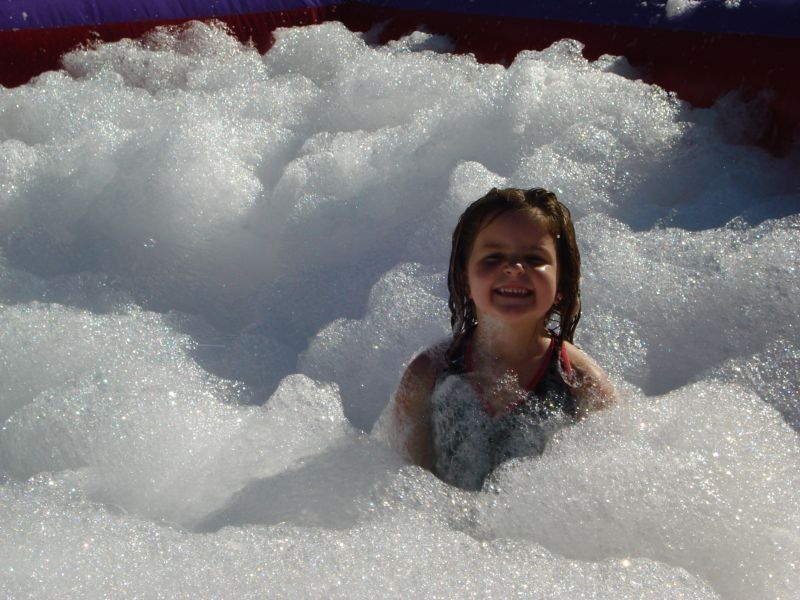 A little girl is sitting in a pool of foam.