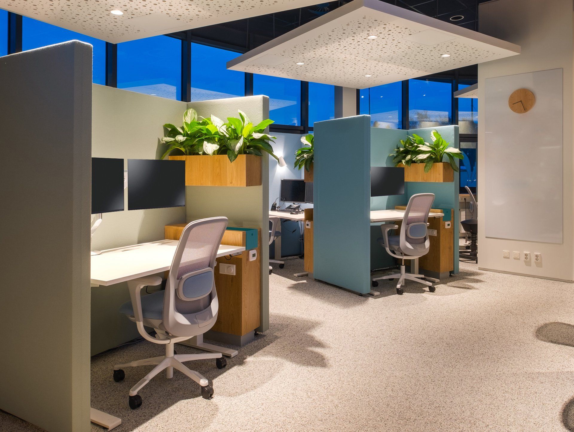 Na verbouwing: Een moderne, open, vitaal callcenter met individuele werkplekken, voorzien van bureaus en stoelen van licht hout en planten in potten klant contact centrum van het Gemeentehuis van Rijswijk, interieurontwerp door KuóStudio