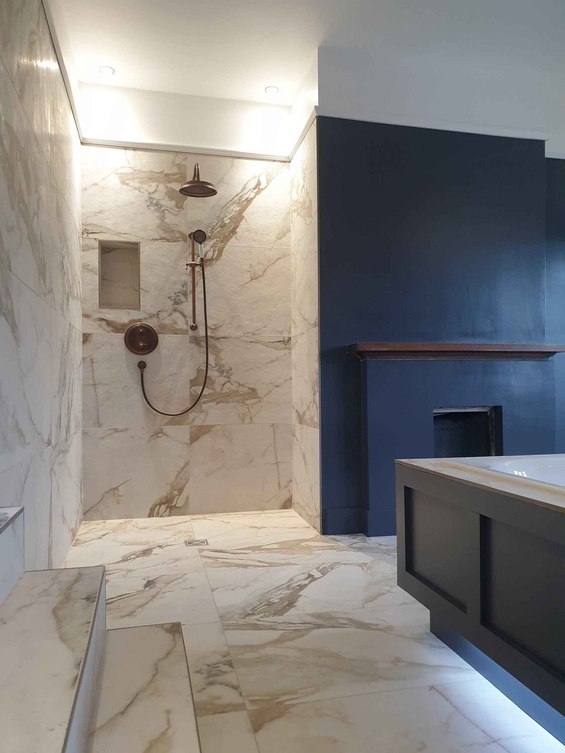 Luxury marble bathroom with walk-in shower and dark vanity.