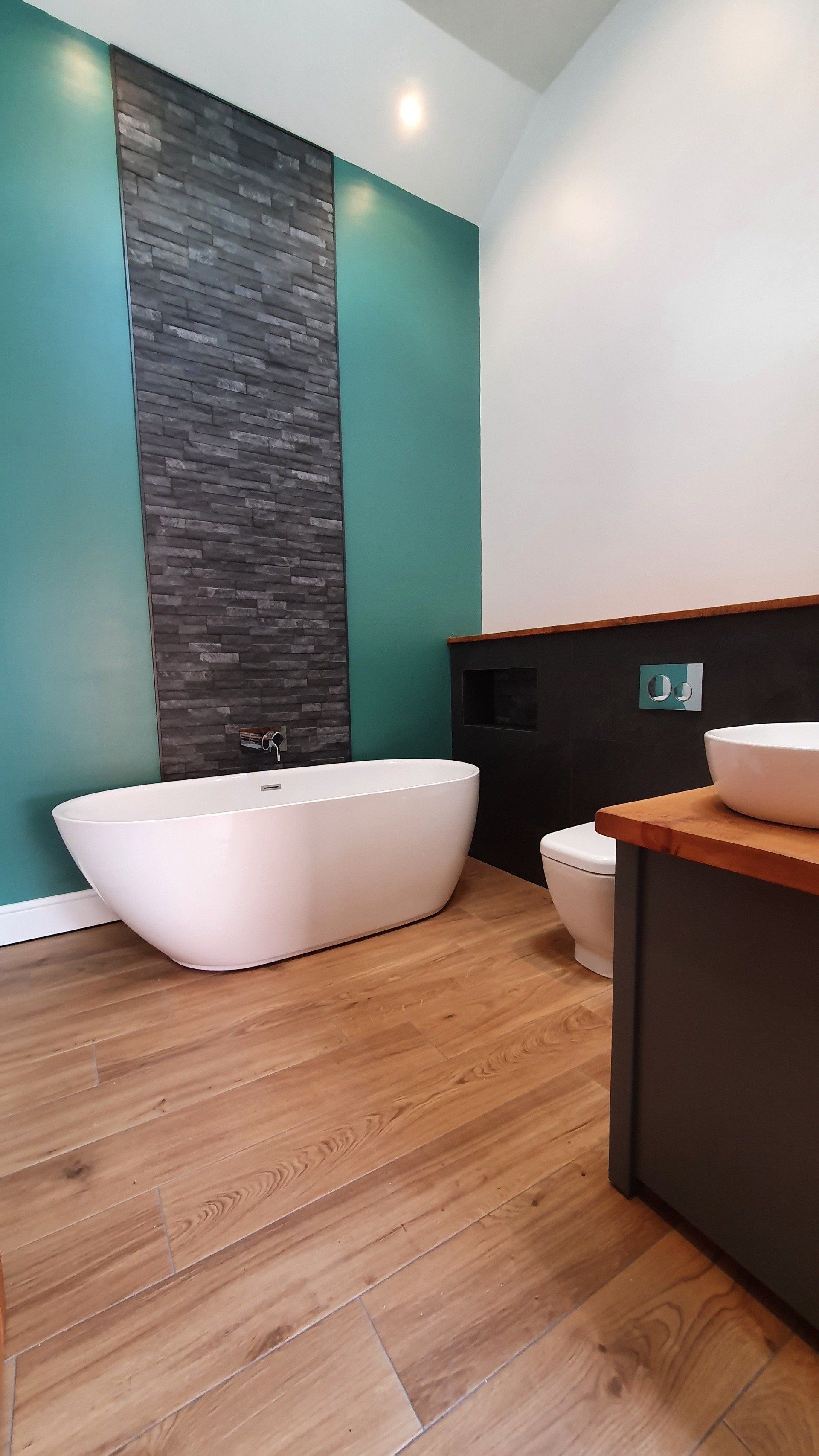 Contemporary bathroom with freestanding bath and teal feature wall.