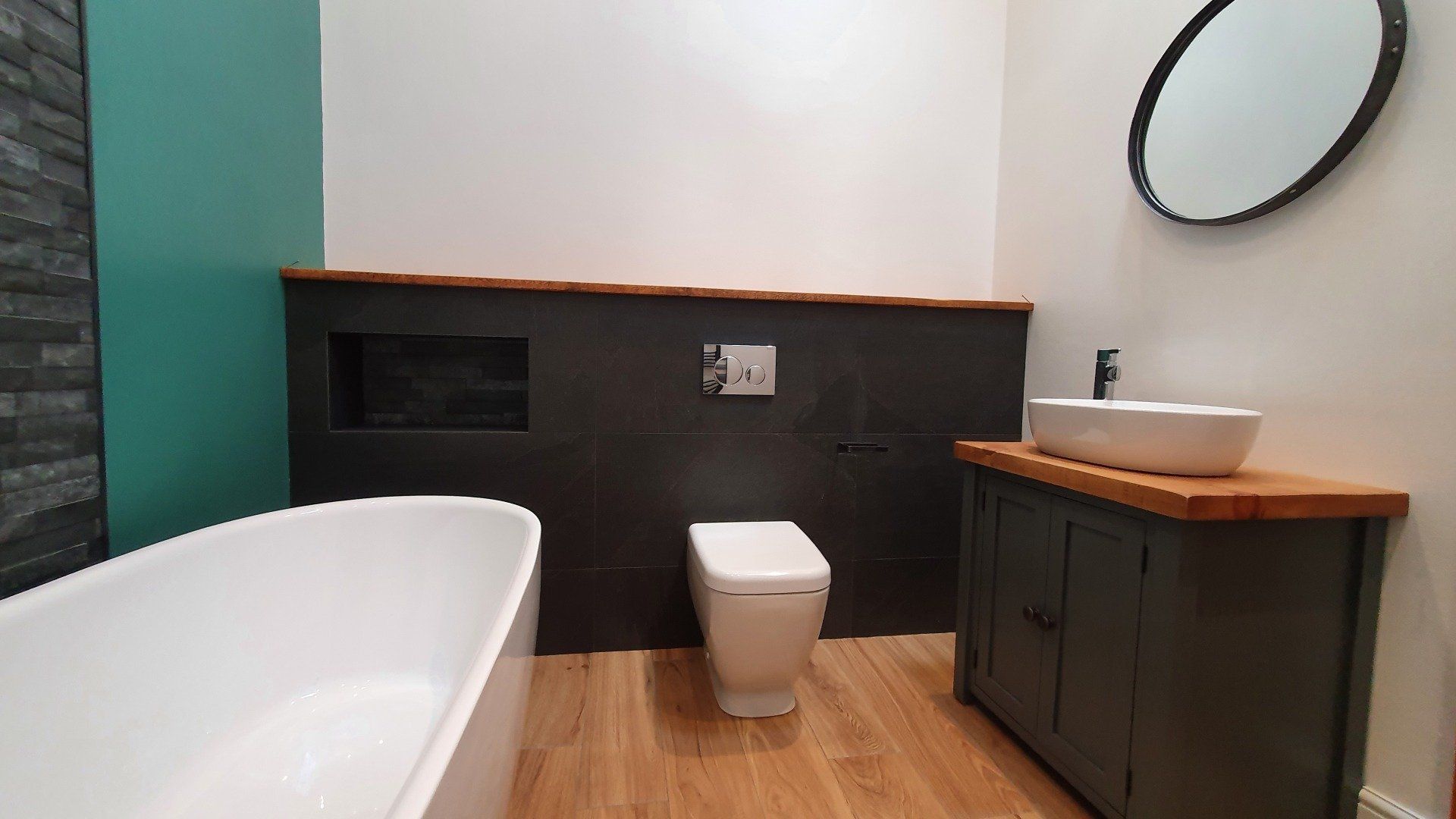 Modern bathroom with bath, wall-hung toilet and dark wood panelling.