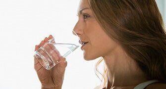 Woman drinking a glass of water — Saxton Well Service in Tinonesta, PA Woman drinking a glass of water — Saxton Well Service in Tinonesta, PA