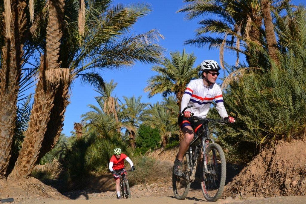 Mountainbikers genieten van het uitzicht op de Draa-vallei tijdens de reis.