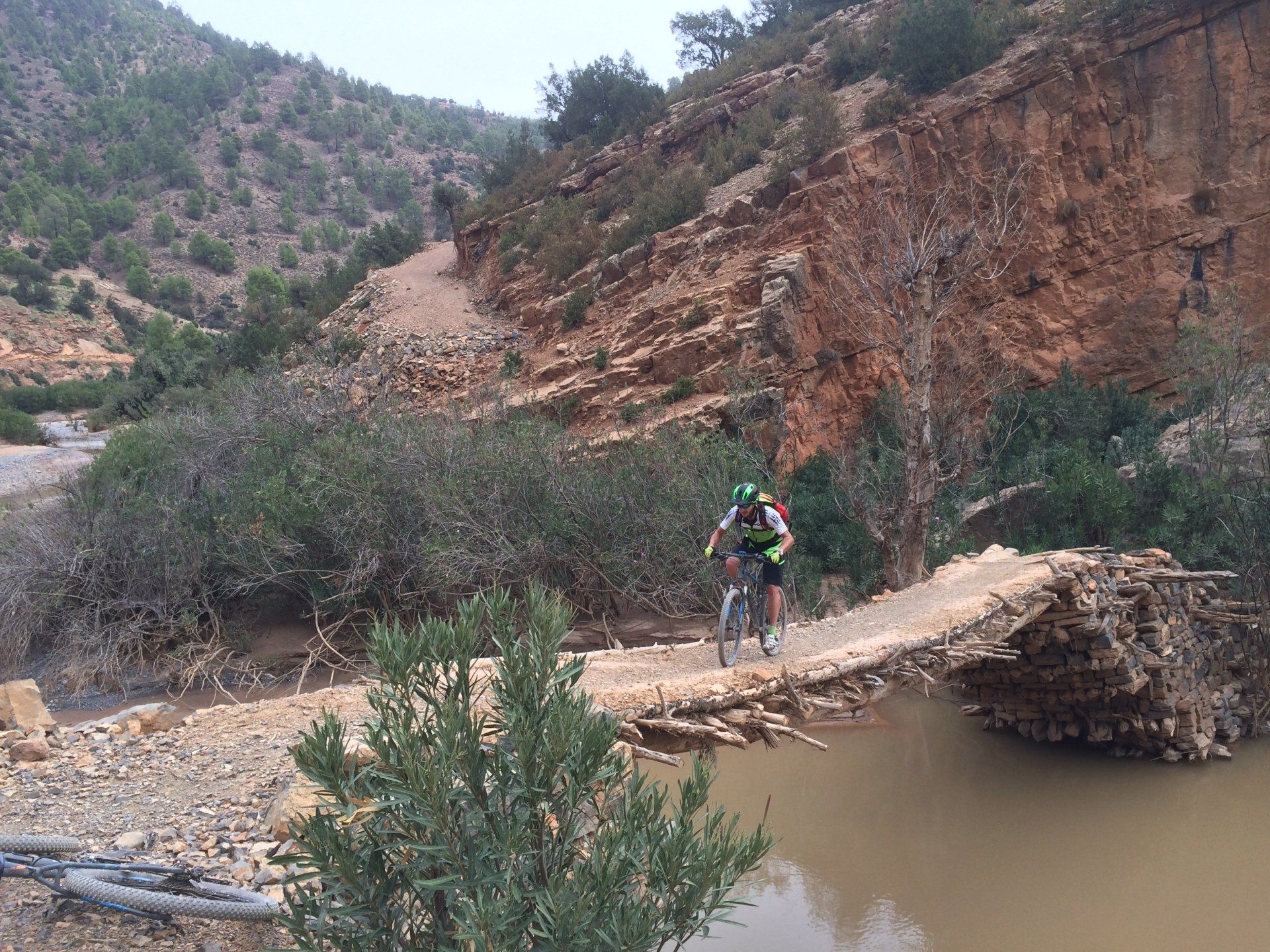 Mountainbiker steekt rivier over via een indrukwekkend bruggetje.