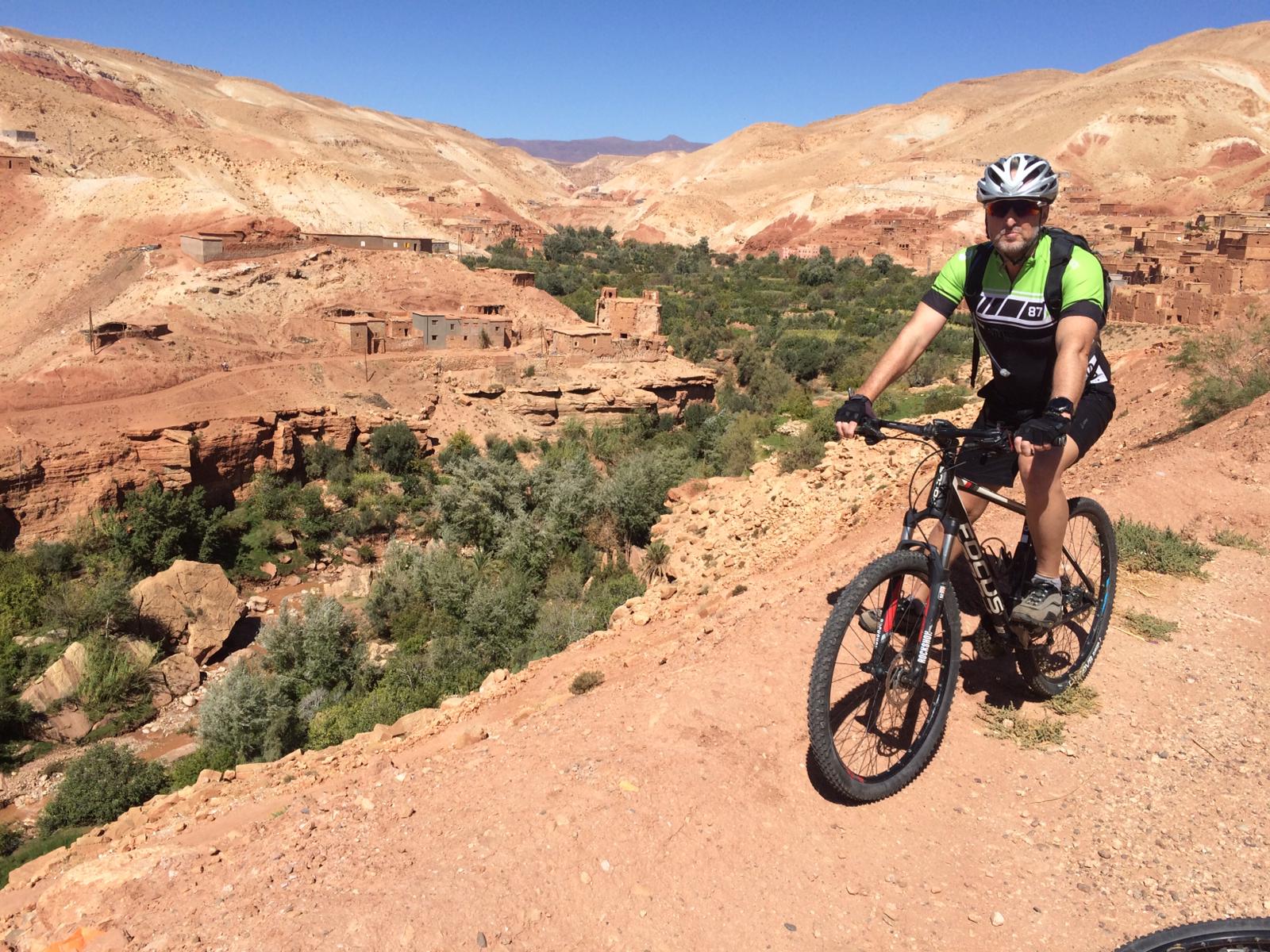 Mountainbiker beklimt de pas bij Boutharar en geniet van een schitterend uitzicht over de gevarieerde vallei
