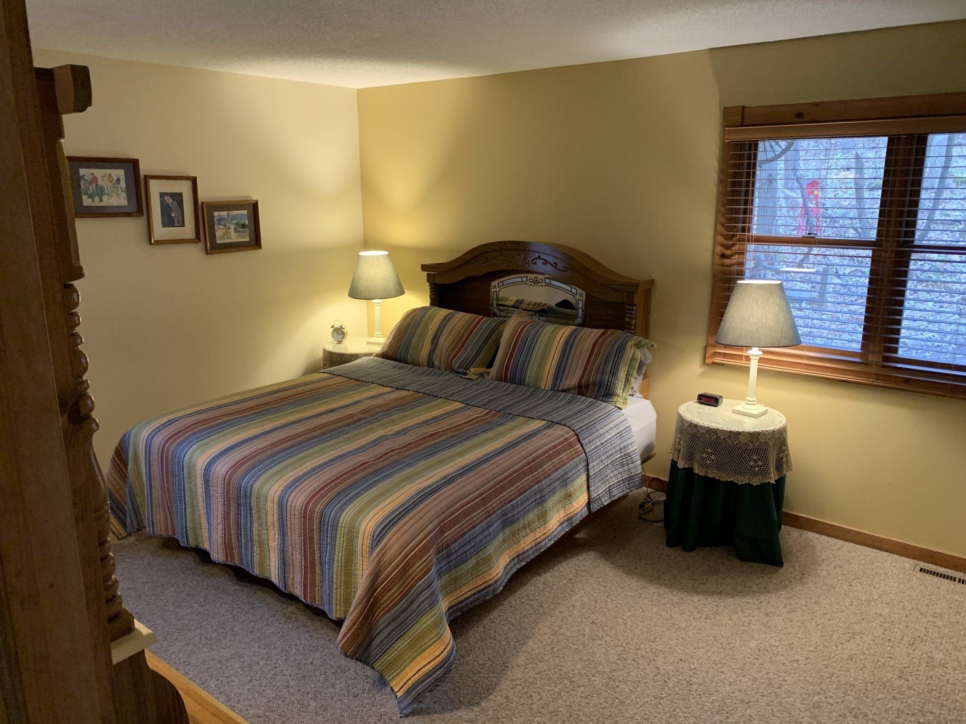 Bedroom with a bed, nightstands, lamps, window, and artwork on the wall.