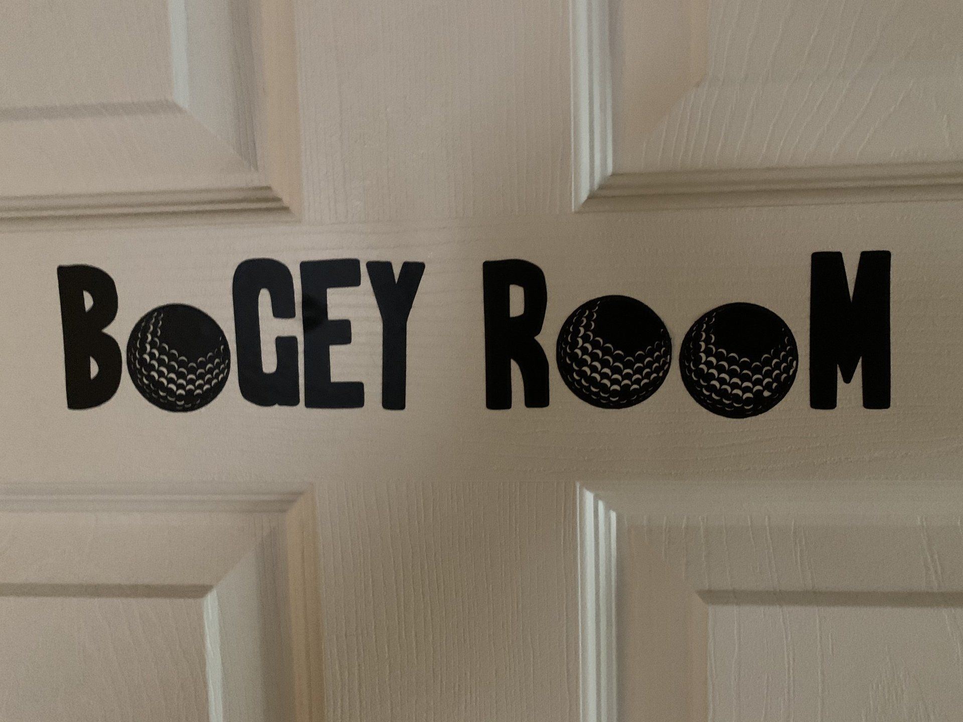 White door with black text and golf ball designs that reads 