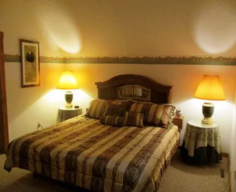 Bedroom with striped bedspread, two lamps on nightstands, and a framed picture.