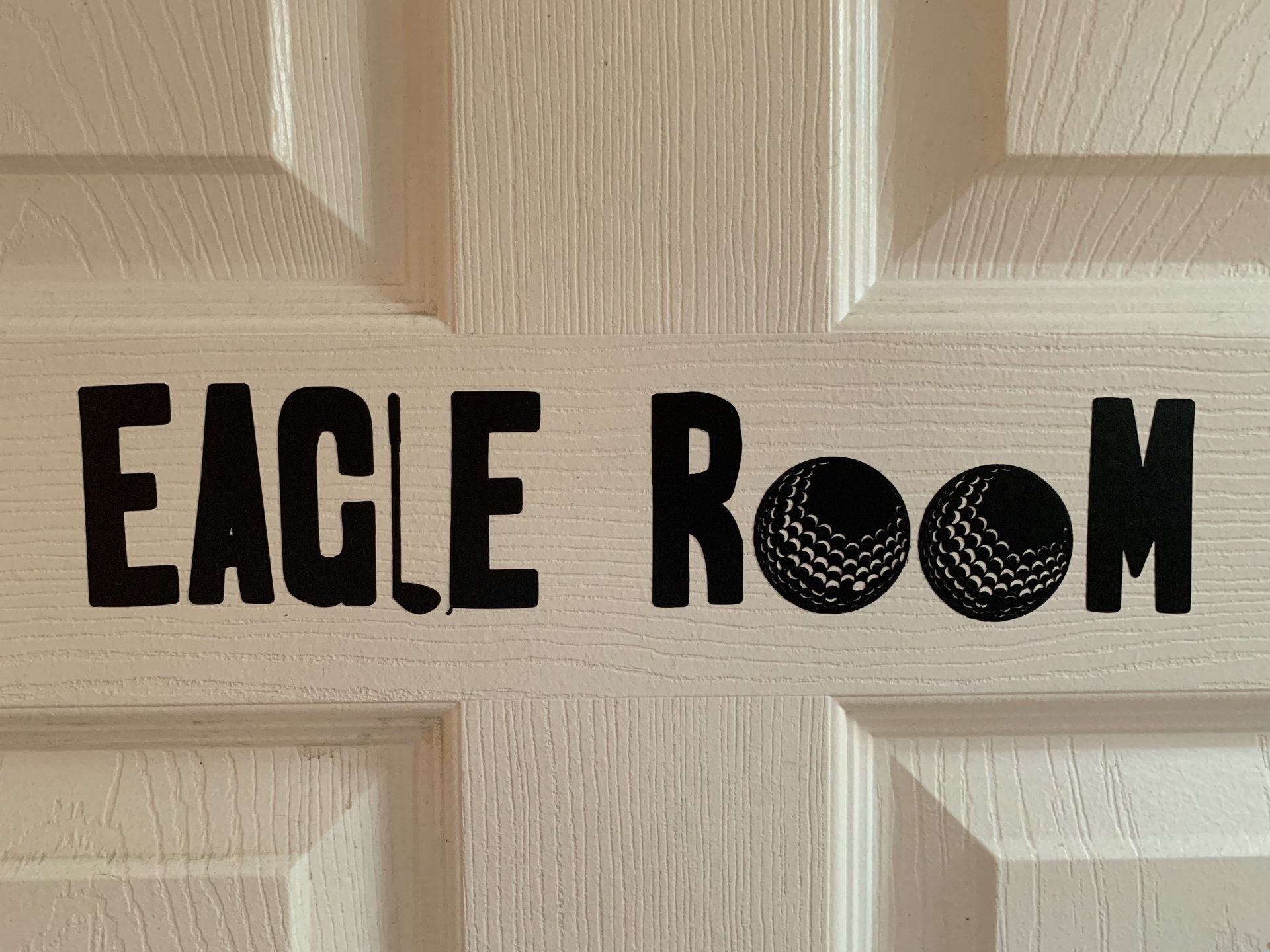 White door with black text and golf ball graphics reading 