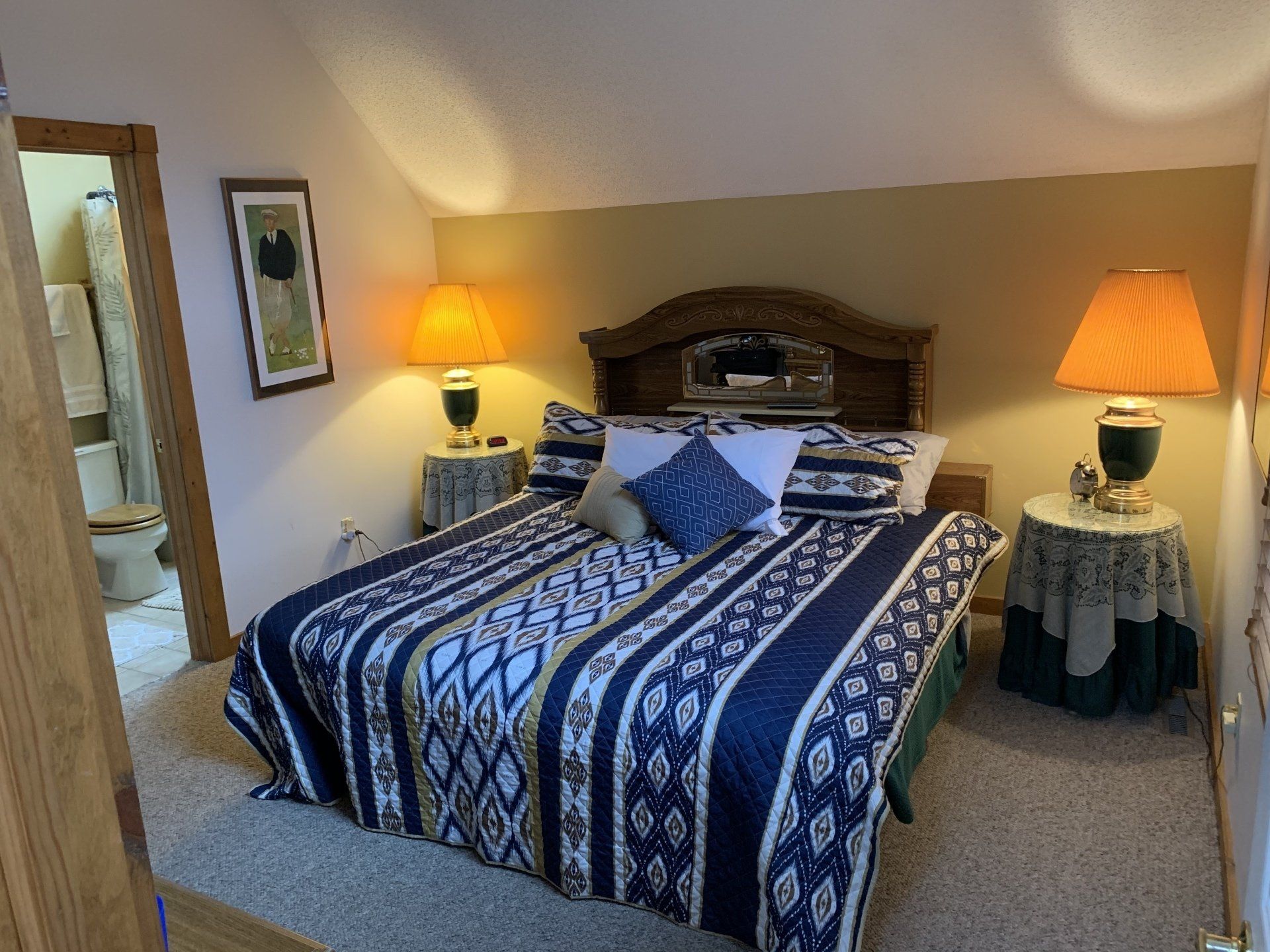 Bedroom with bed, nightstands, lamps, and en-suite bathroom.