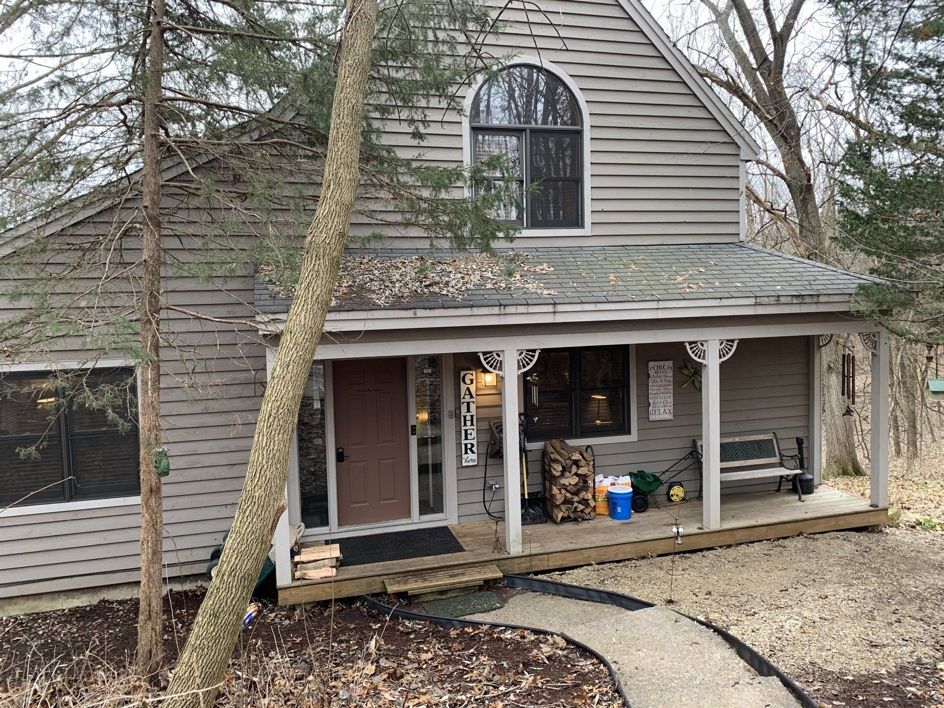 Tan cottage with porch, walkway, and trees.