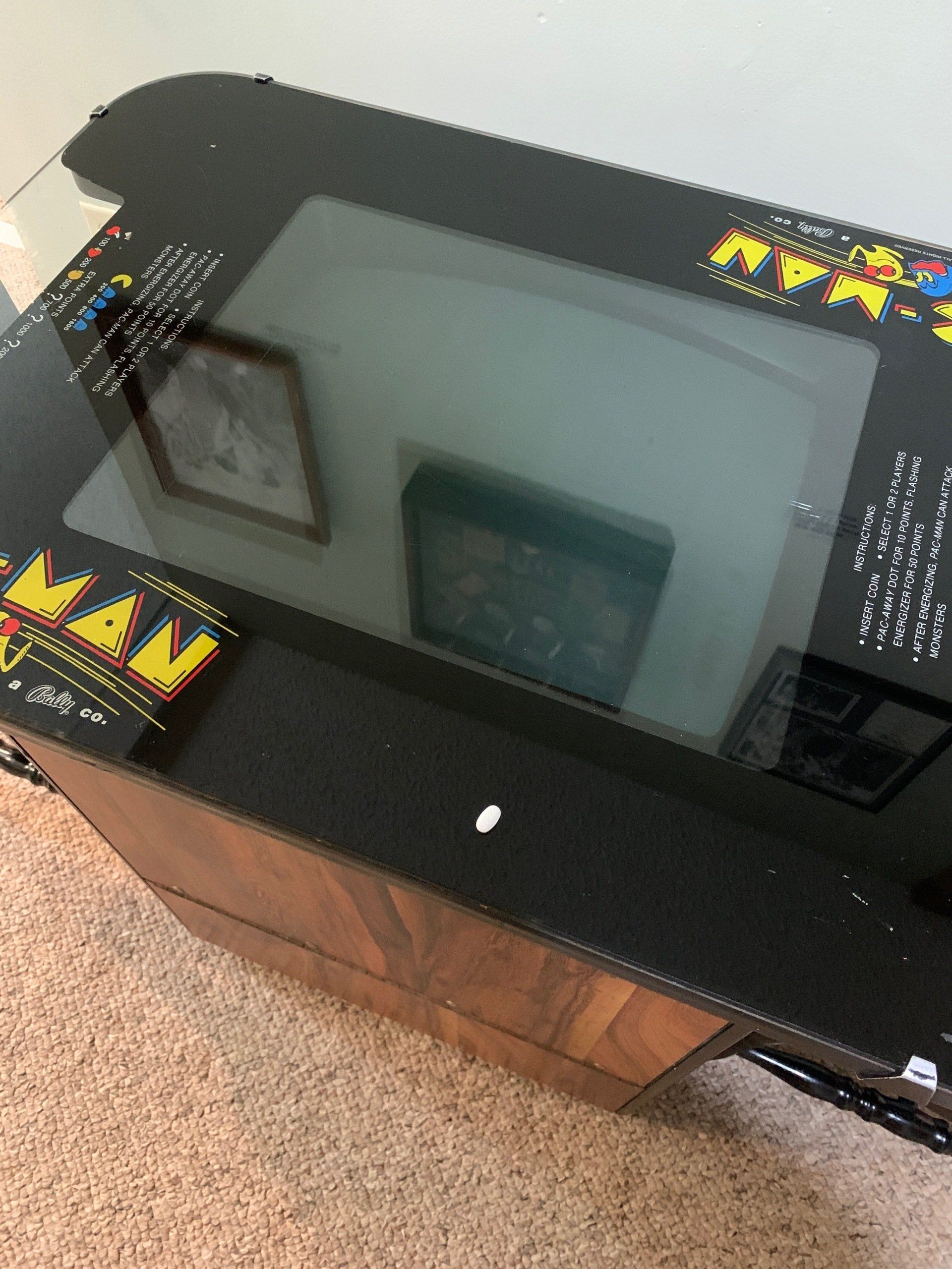 Pac-Man arcade game table with a glass top, set on a brown wooden cabinet.