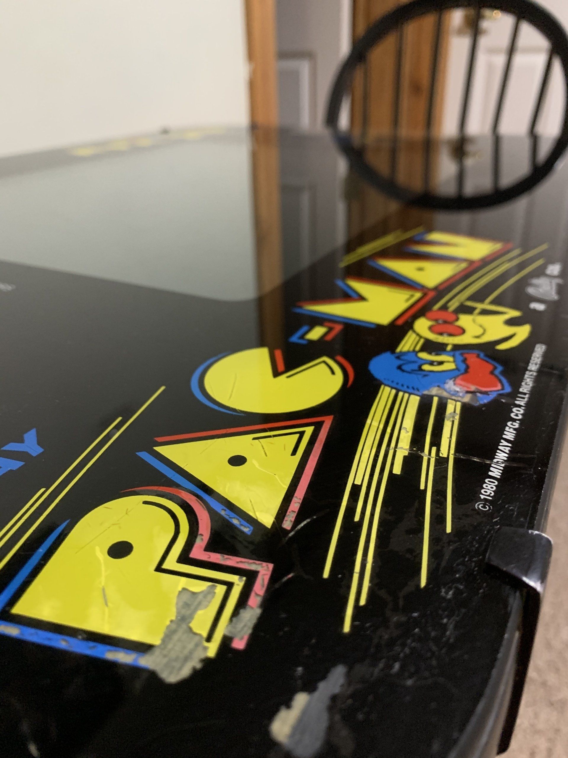 Close-up of a Pac-Man arcade game table, showing the logo with yellow, blue, and black colors.