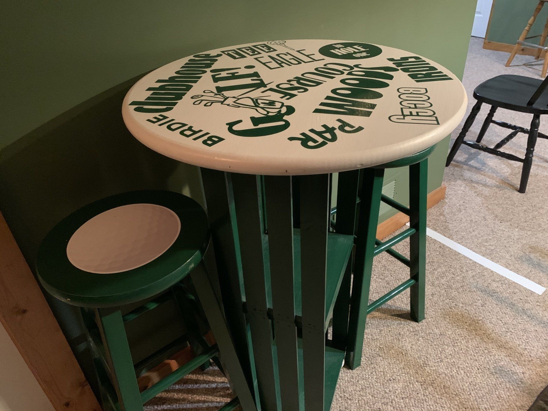 Green and white round table and stool with golf terminology printed on the table top.