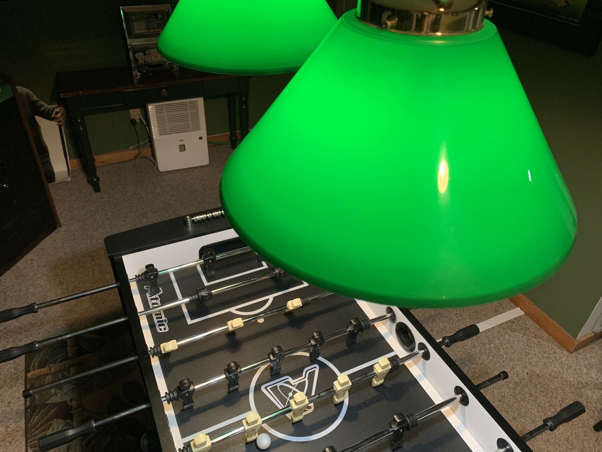 Foosball table under bright green lamps.