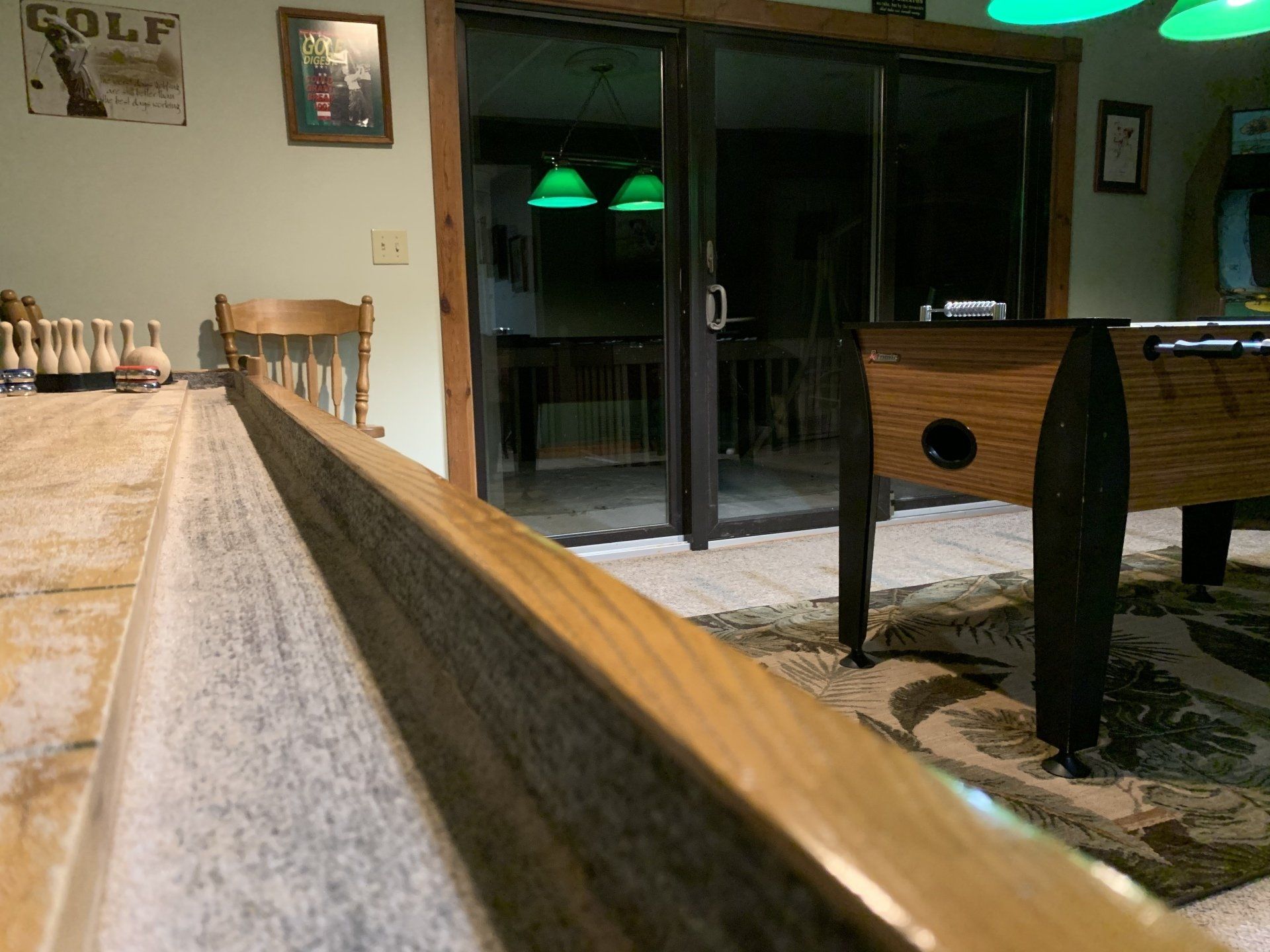 Foosball table and counter with items on it in a room, sliding glass doors in the background.