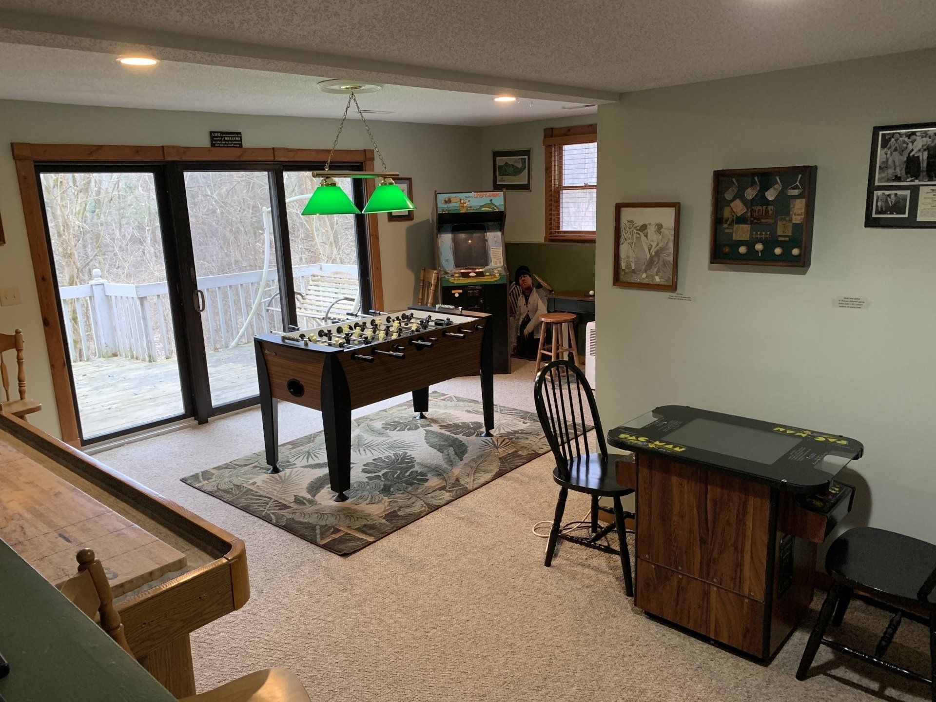 Game room with foosball table, arcade game, sliding glass door, and shuffleboard.