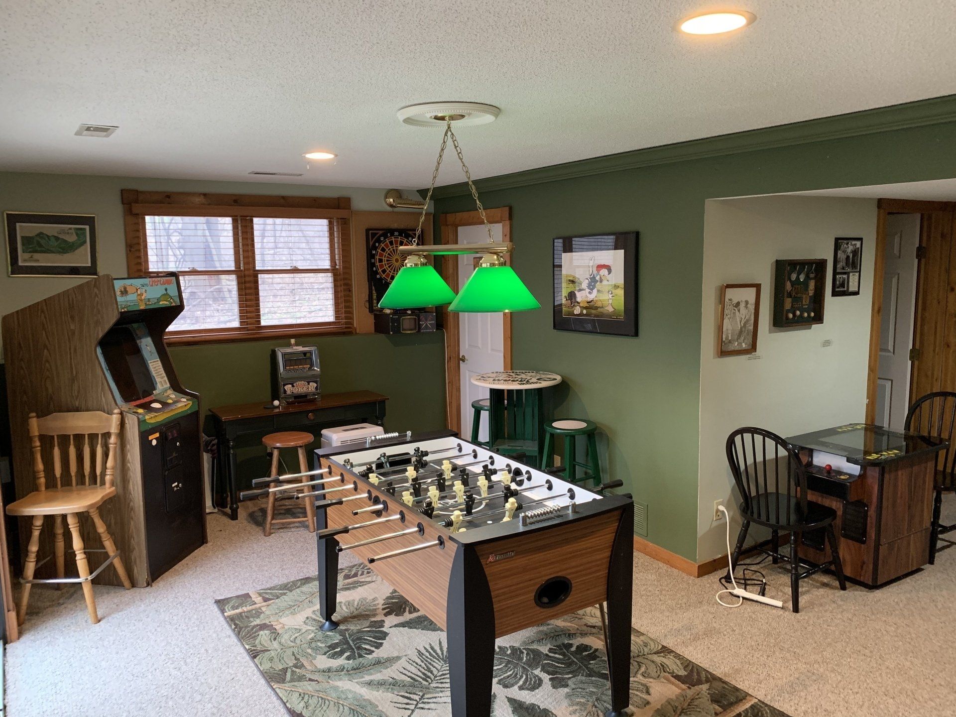 Game room with arcade game, foosball table, and green walls.