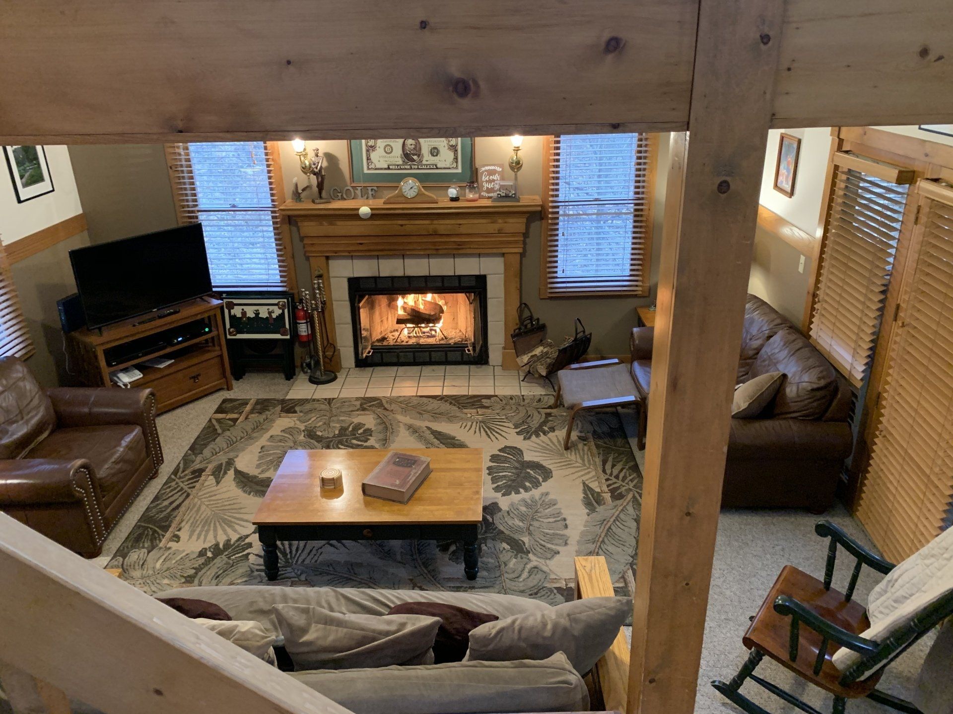 Living room with fireplace, wooden beams, two sofas, and area rug.