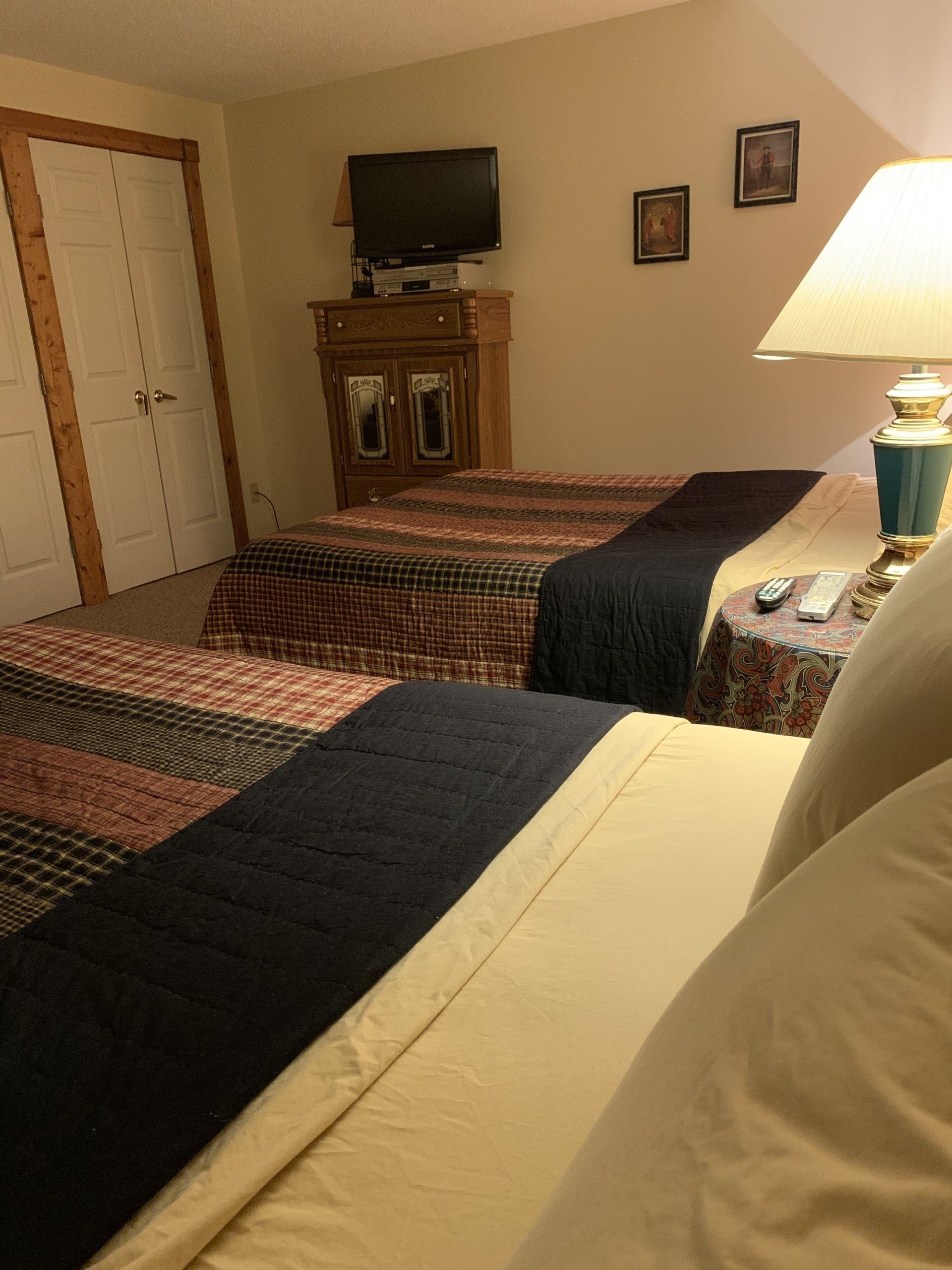 Two beds in a hotel room with a TV, a nightstand, and a dresser.