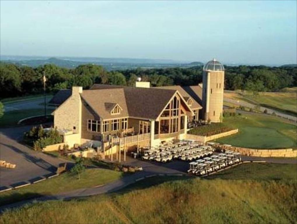 Golf course clubhouse with golf carts, grassy hills, and a distant view.