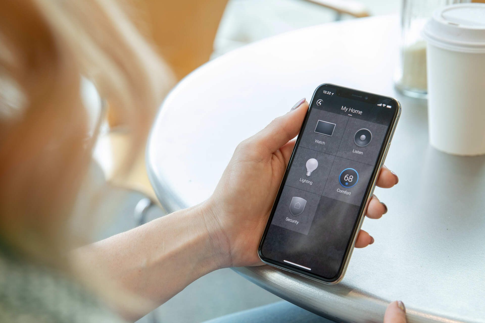 A person is holding a smart phone in their hand while sitting at a table.