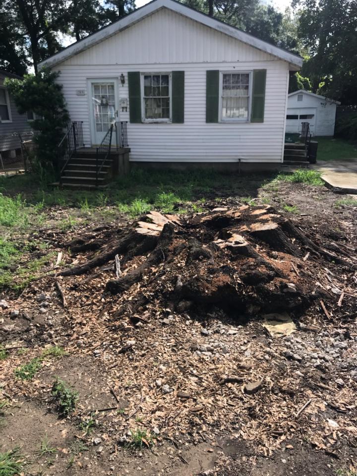 A white house with green shutters and a pile of dirt in front of it.
