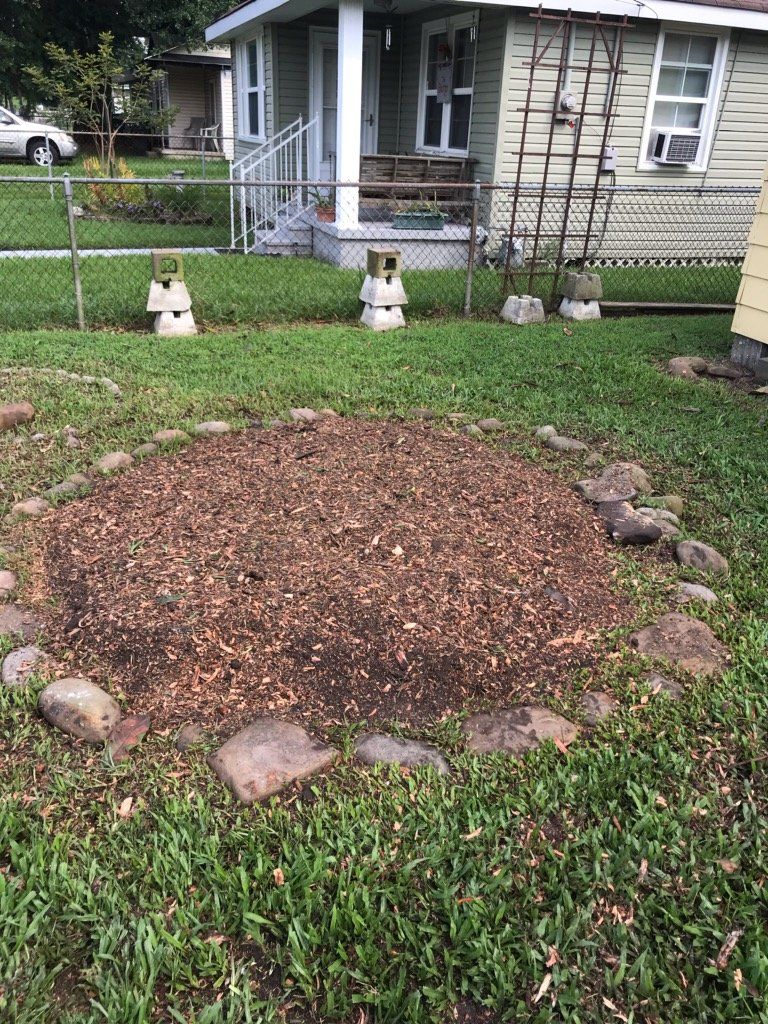 A circle of rocks in the grass in front of a house.