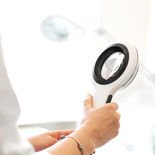 Dermatologist Holding a Magnifying Glass — Charleston, WV — H. Richard Reynolds, M.D.