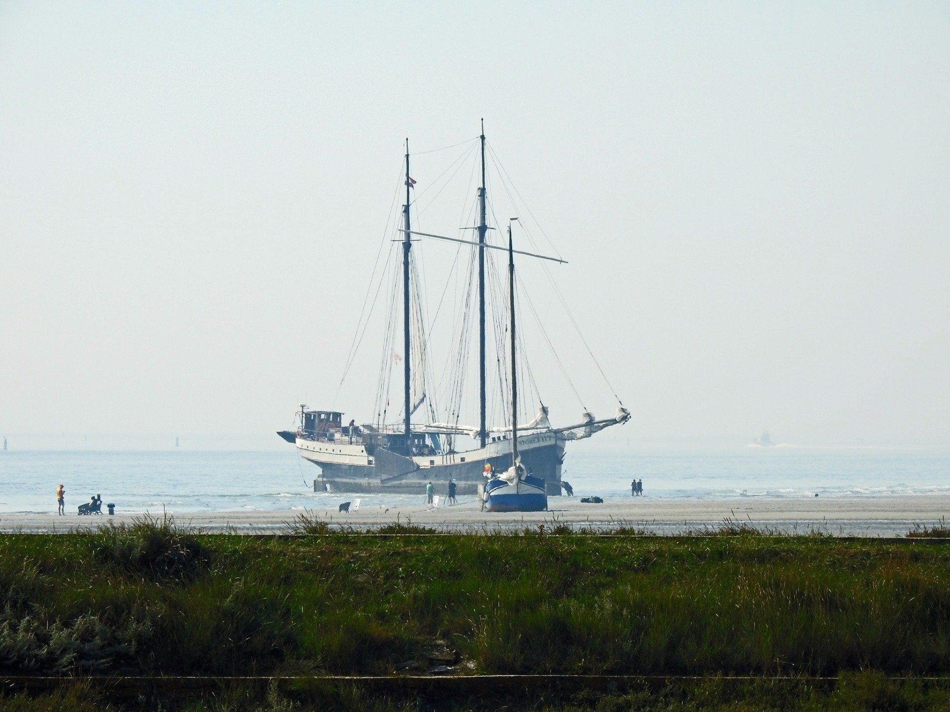 Sailing ship dried out on the beach at Terschelling, with green dunes in the background.