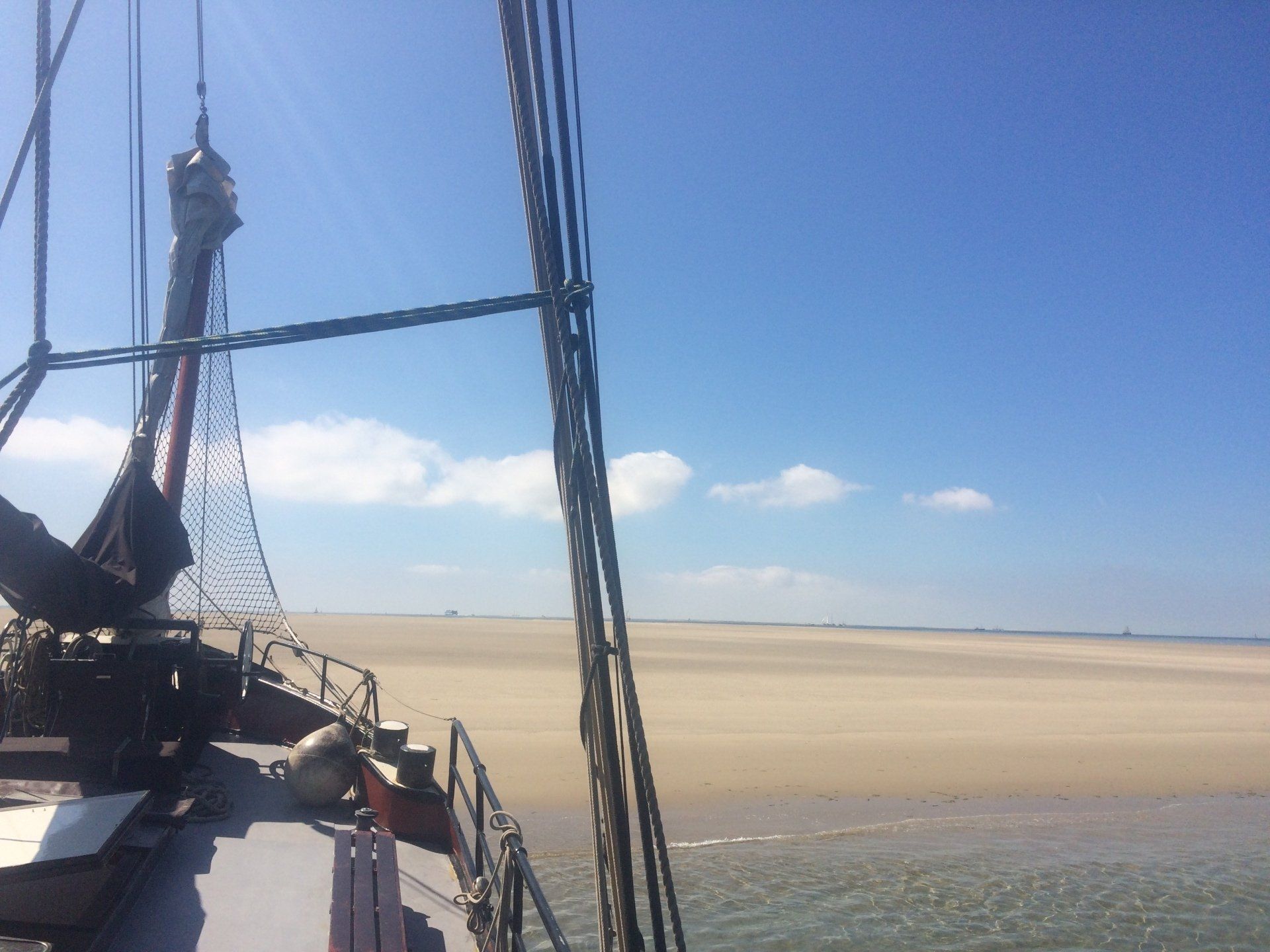 View from the deck to a wide beach under a blue sky with clouds in the Dutch Wadden Islands.