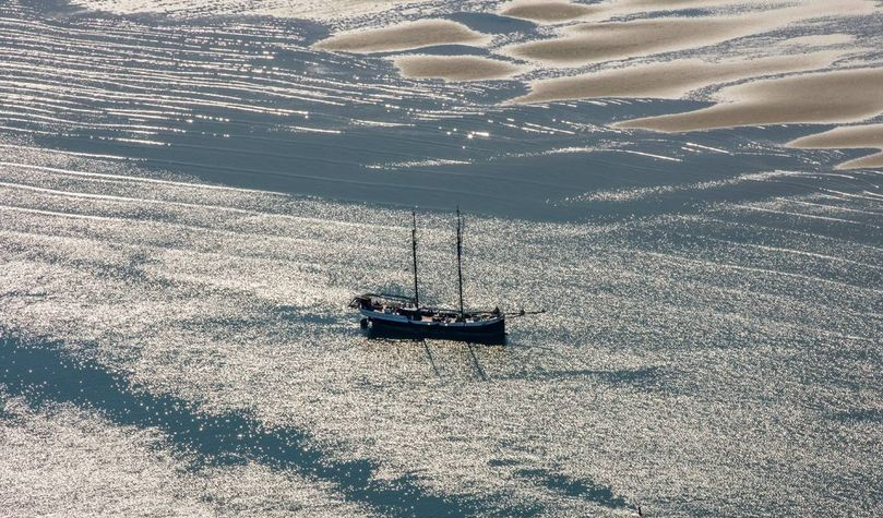 Aerial photo of a tall ship dried out on the Richel sandbank in the Dutch Wadden Sea at low tide.