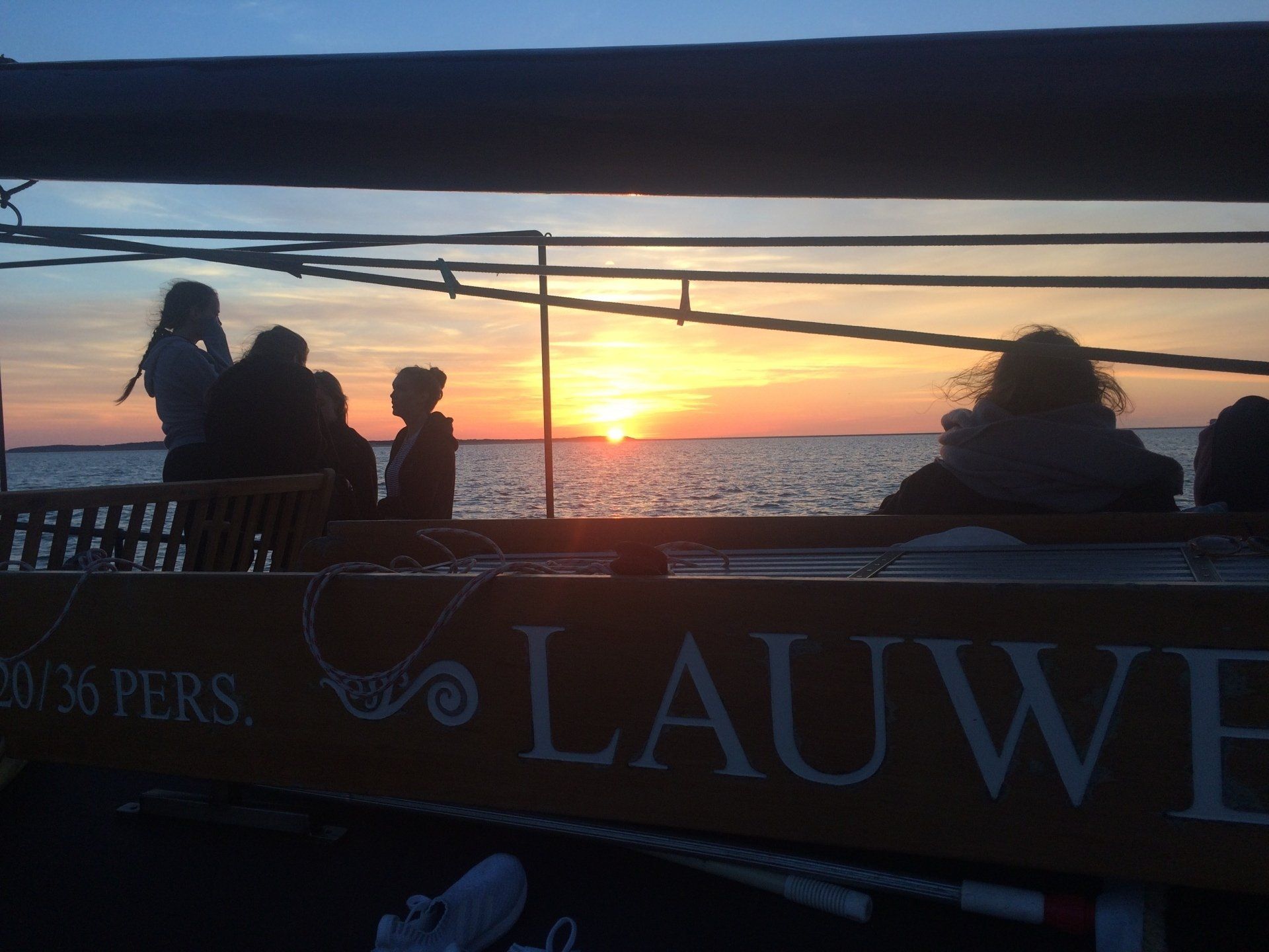 People on board watching the sunset over the sea during a sailing trip in the Netherlands.