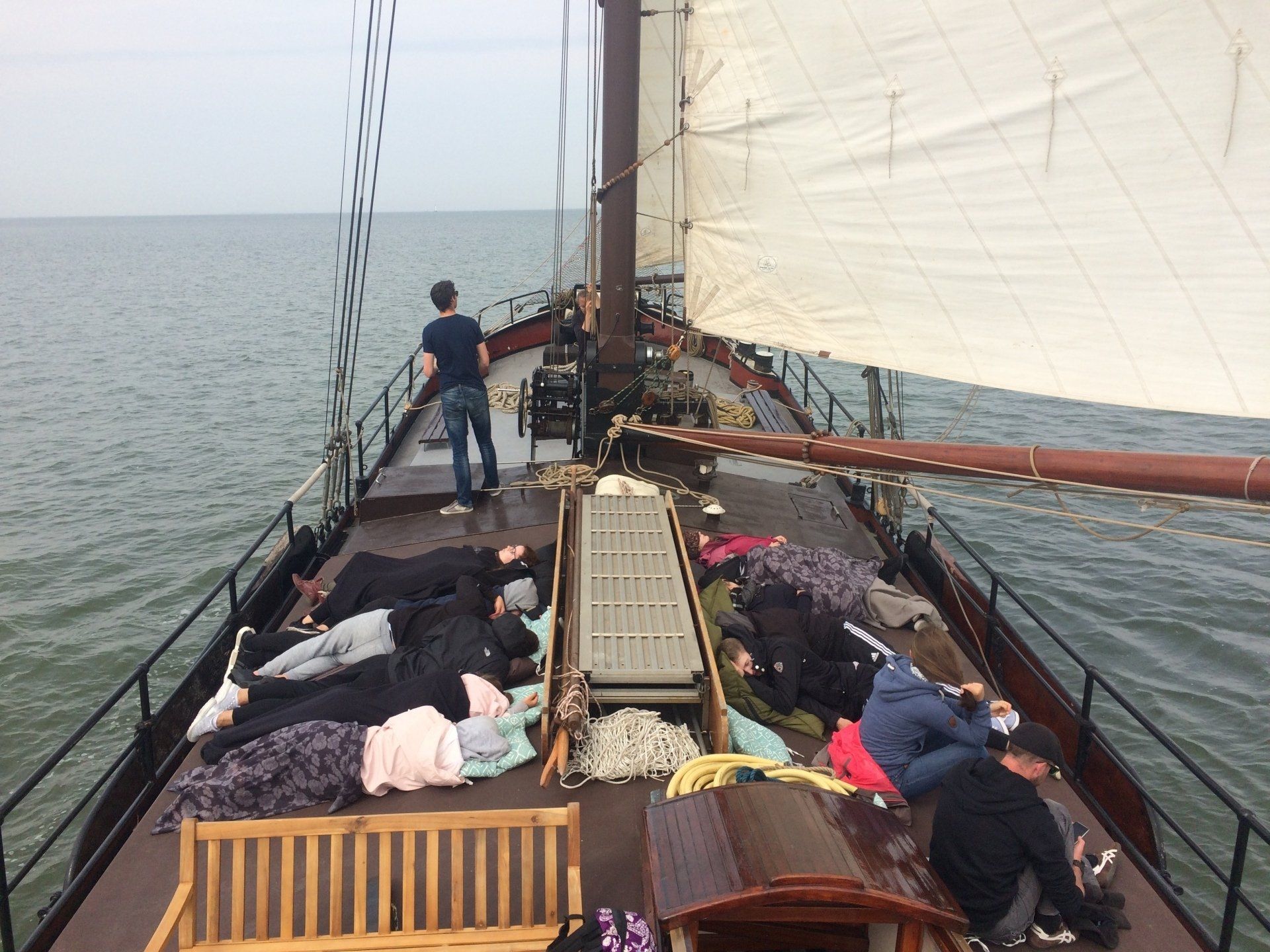 Relaxing on deck on open water with sails set, enjoying a traditional sailing trip in the Netherlands.