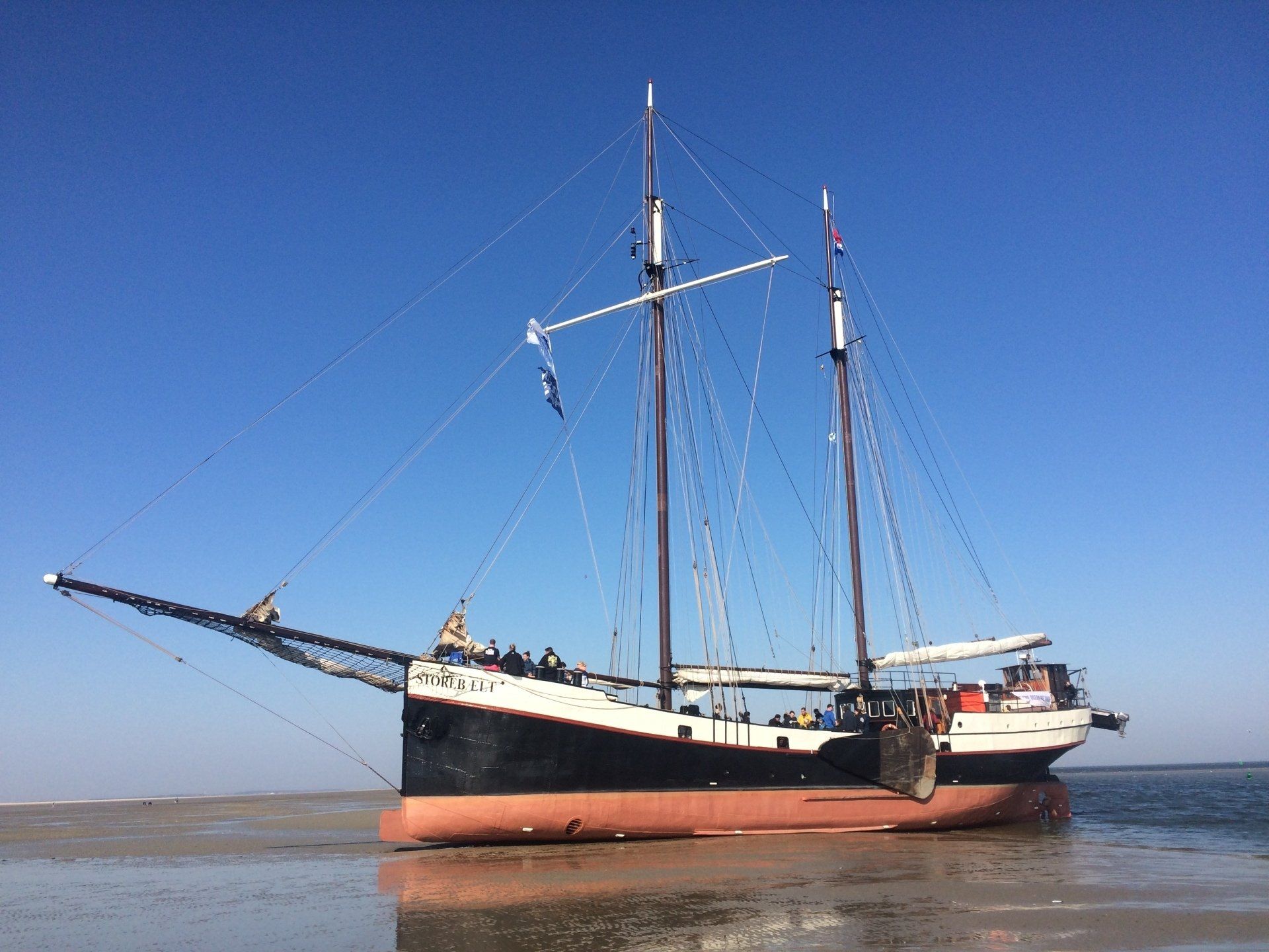 Traditional flat-bottomed boat dried out on the Dutch Wadden Sea, dark hull with a red waterline.