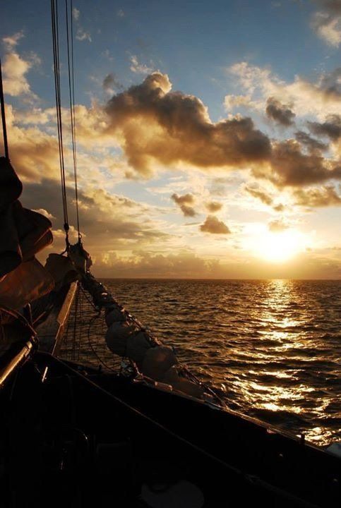 Golden sunset seen from a boat, with warm light on the water and clouds over the Netherlands.