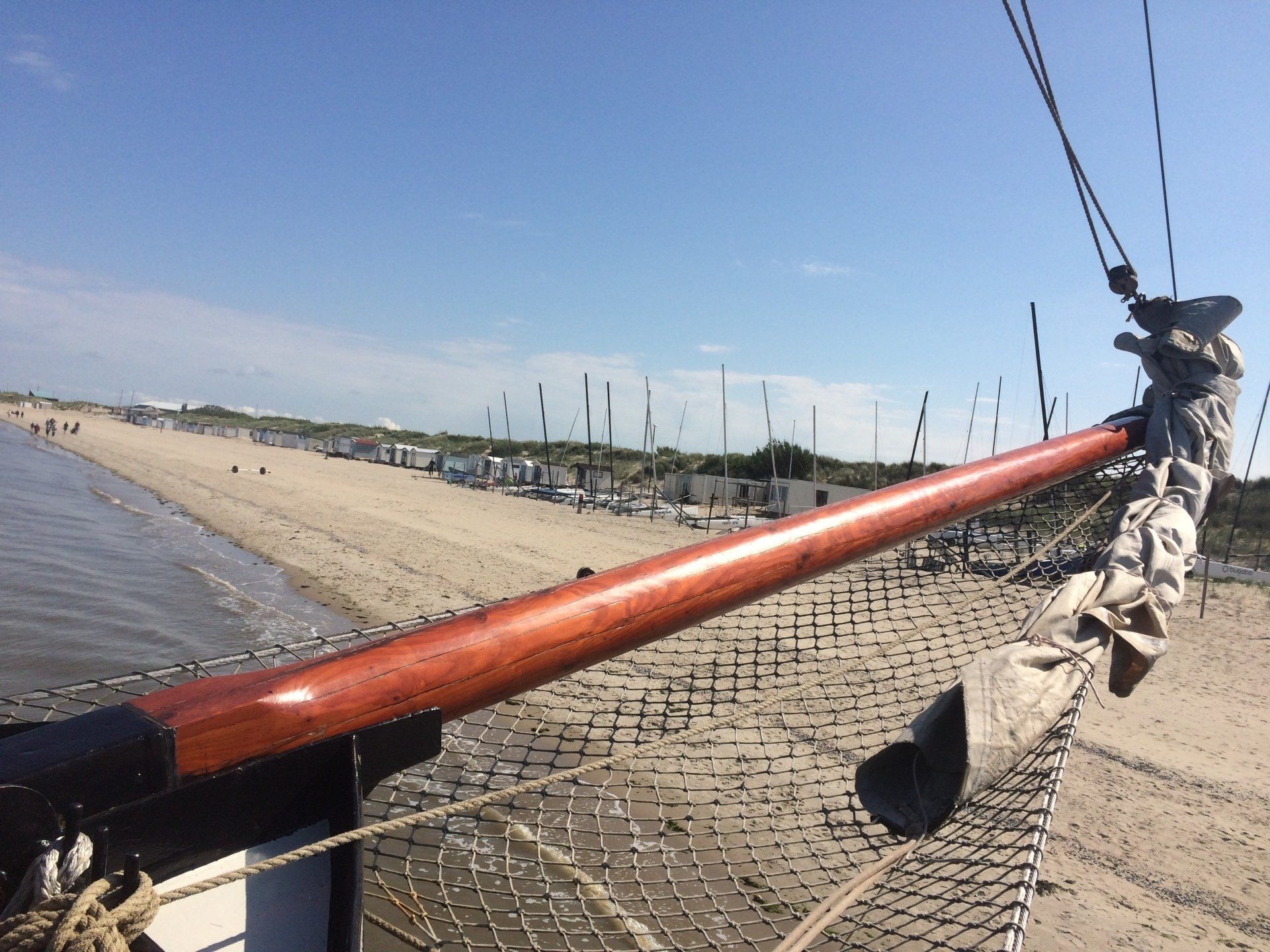 Bow of a wooden ship pointing towards the beach on a sunny day in the Dutch Wadden Islands.