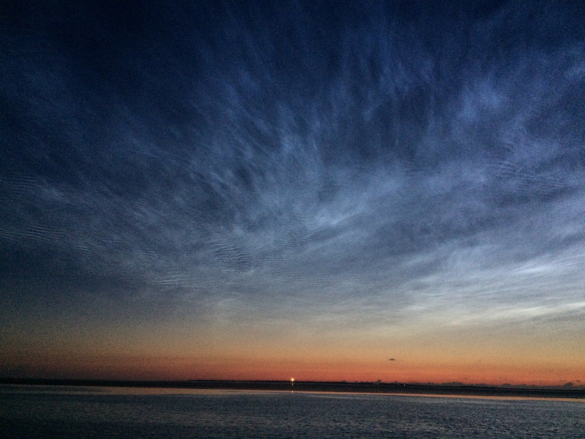 Glowing evening clouds above a calm horizon, deep blue and orange colours over the Dutch coast.