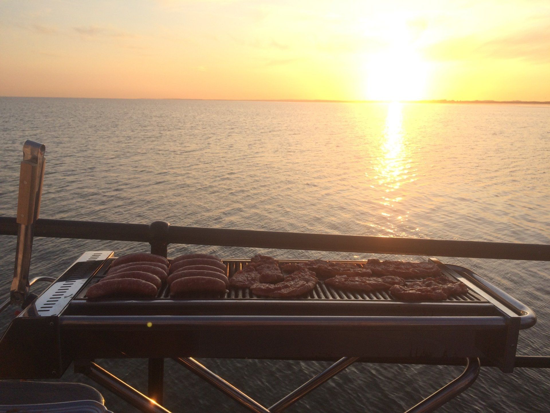 Barbecue on a pier at sunset by the sea in the Netherlands, a relaxed evening in the Wadden region.