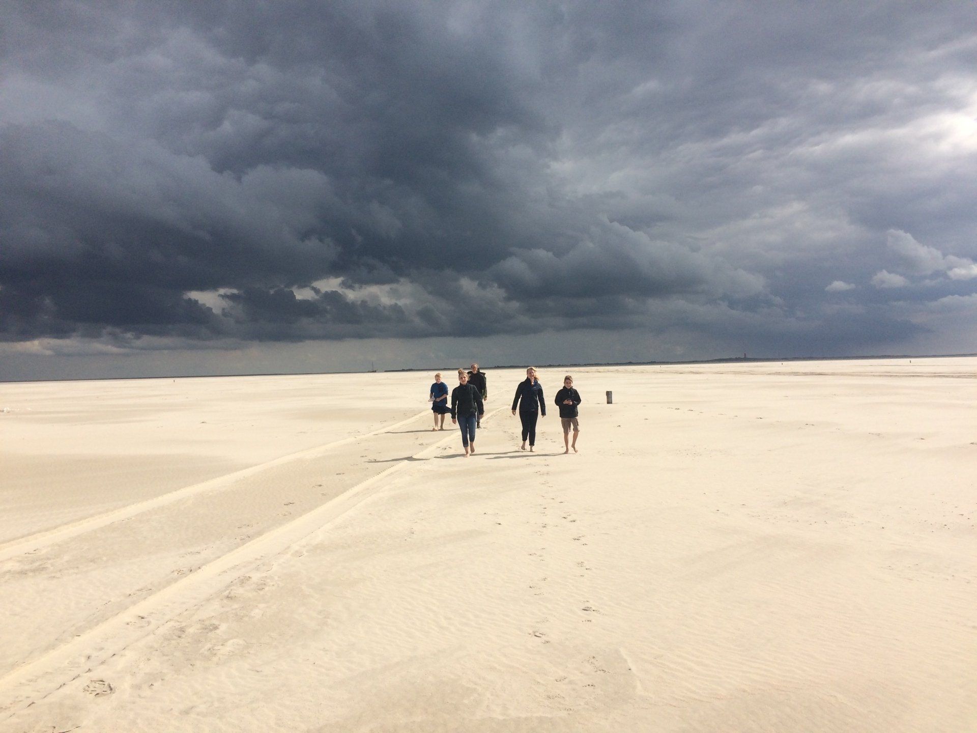 Group walking over dunes under dramatic clouds on a Dutch Wadden Island.
