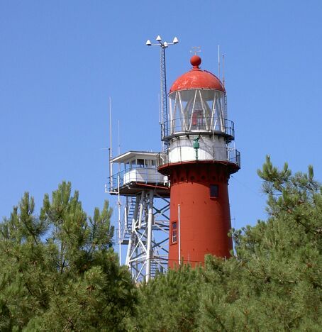 Lighthouse on Vlieland in the Dutch Wadden Islands, framed by trees under a blue sky.