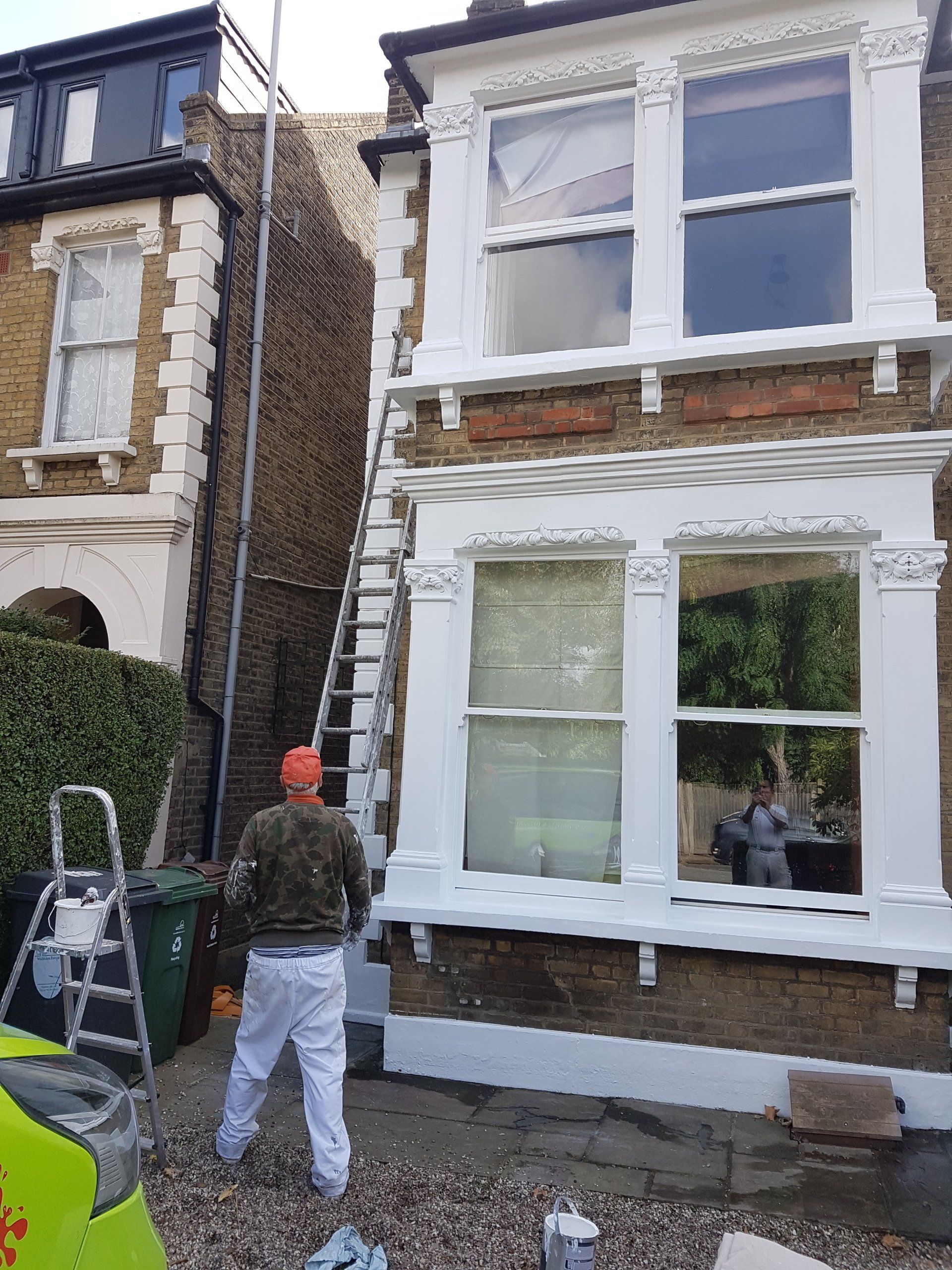 Worker moving ladder outside property