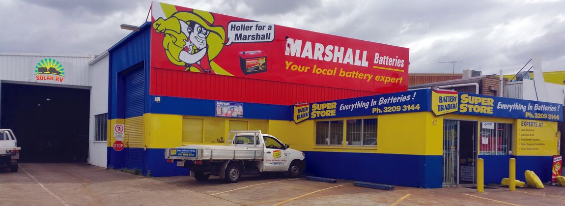 Bright blue Marshall’s Toy Warehouse storefront with red signs and yellow accents in a parking lot