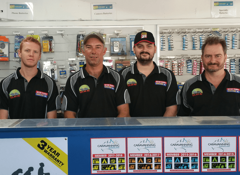 Four men in black team shirts stand behind a counter in a sports shop.