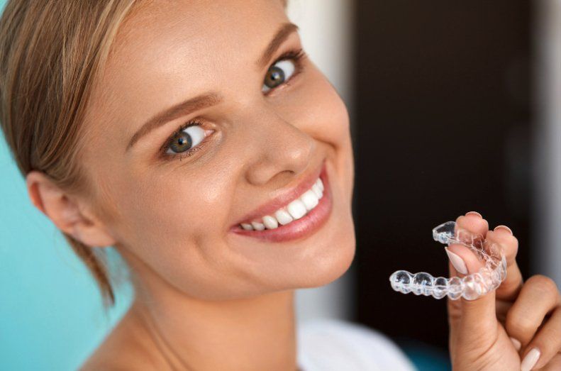 woman holding Invisalign clear aligners and retainers